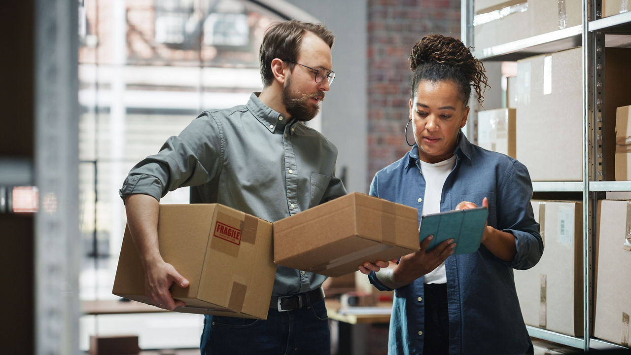 Homme et femme triant des marchandises dans un entrepôt à l’aide d’une tablette