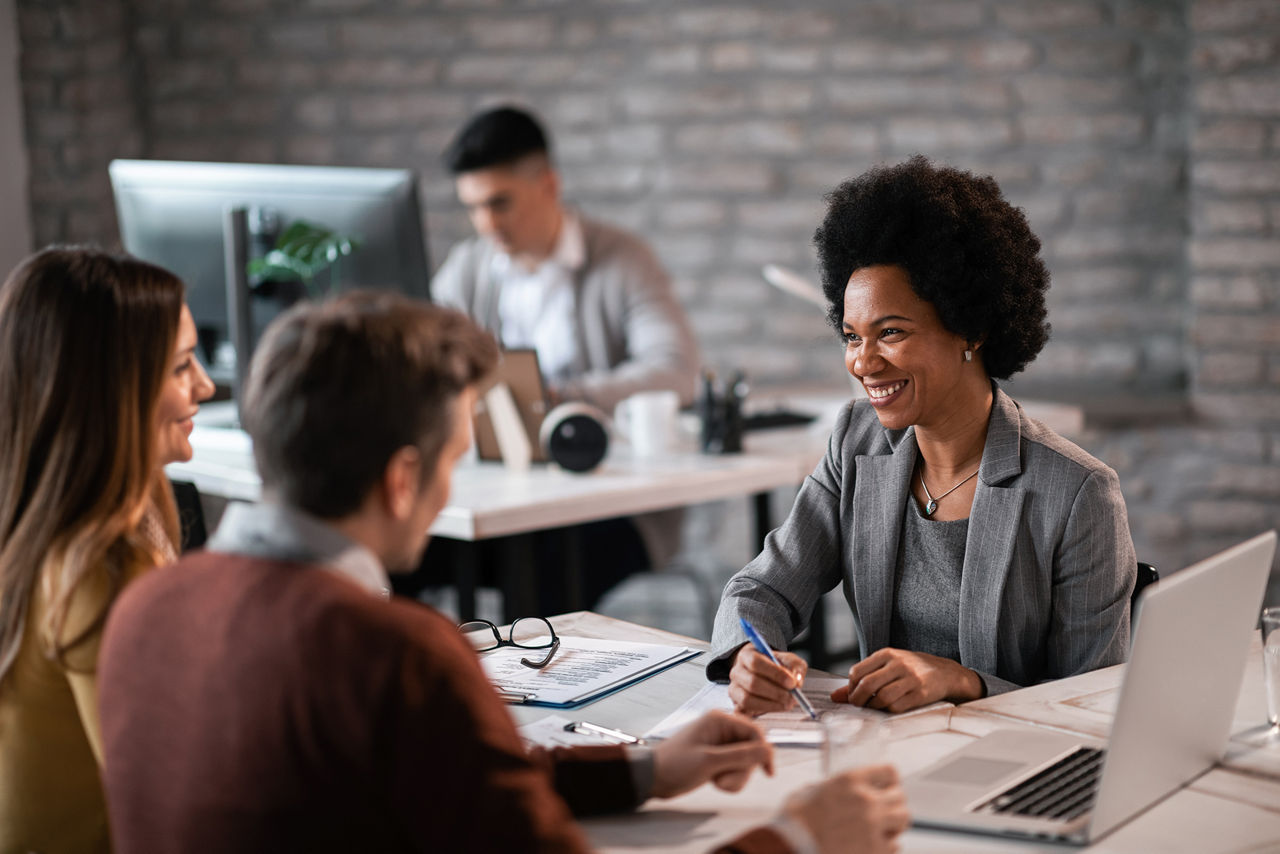 Conseiller financier discutant avec un couple de leur futur investissement lors d’une réunion au bureau