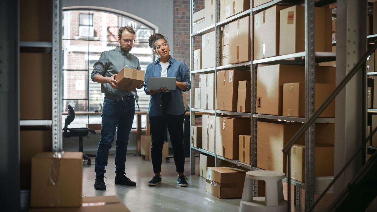 Man and woman sorting goods in a warehouse with tablet