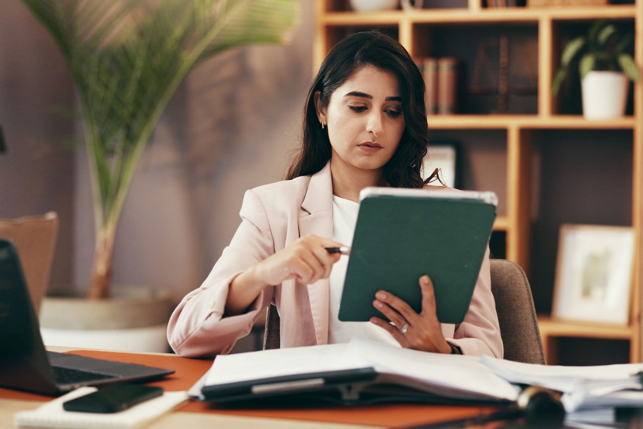 A federal investigator leans over a desk covered with case documents and evidence, analyzing information under a desk lamp in an office setting