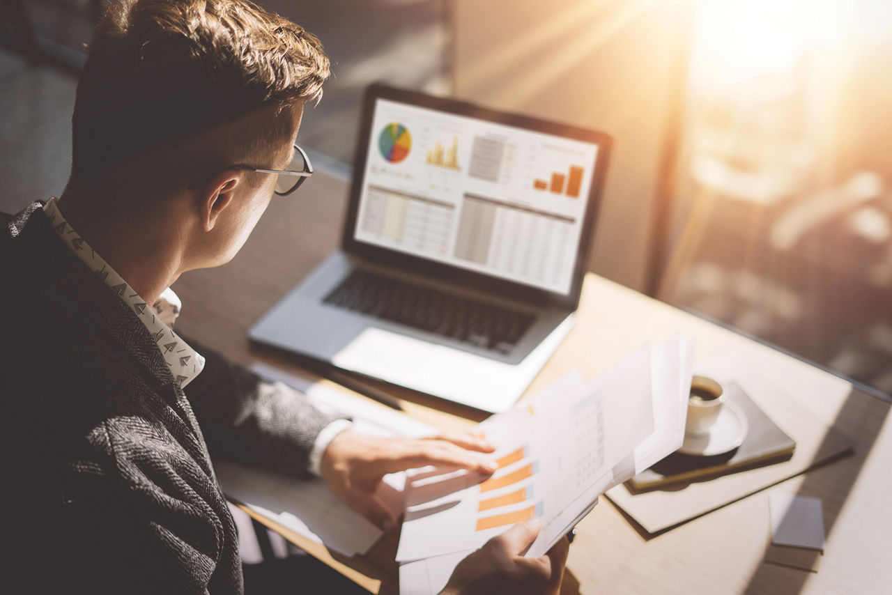 Young finance market analyst works on laptop