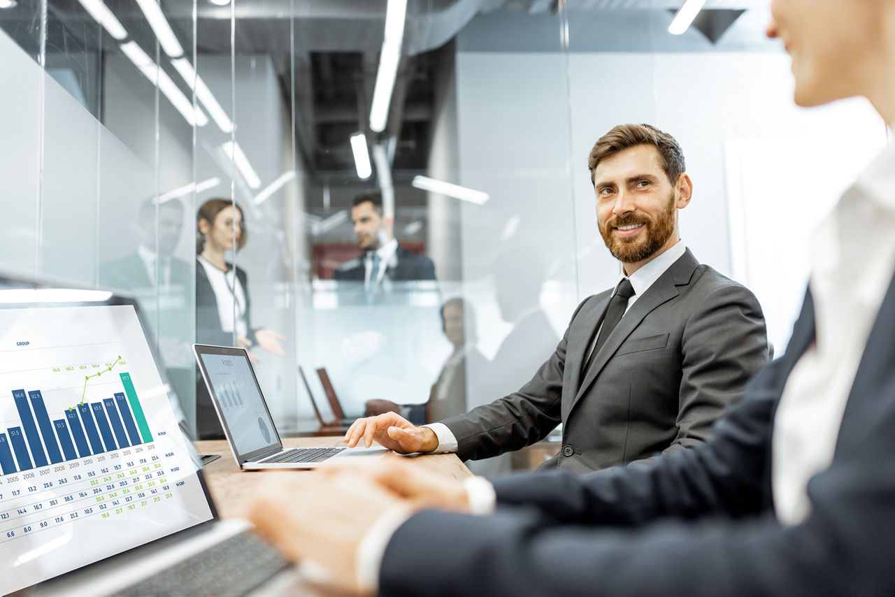 Empleados de cuello blanco trabajando en una computadora portátil en el departamento financiero de una gran corporación