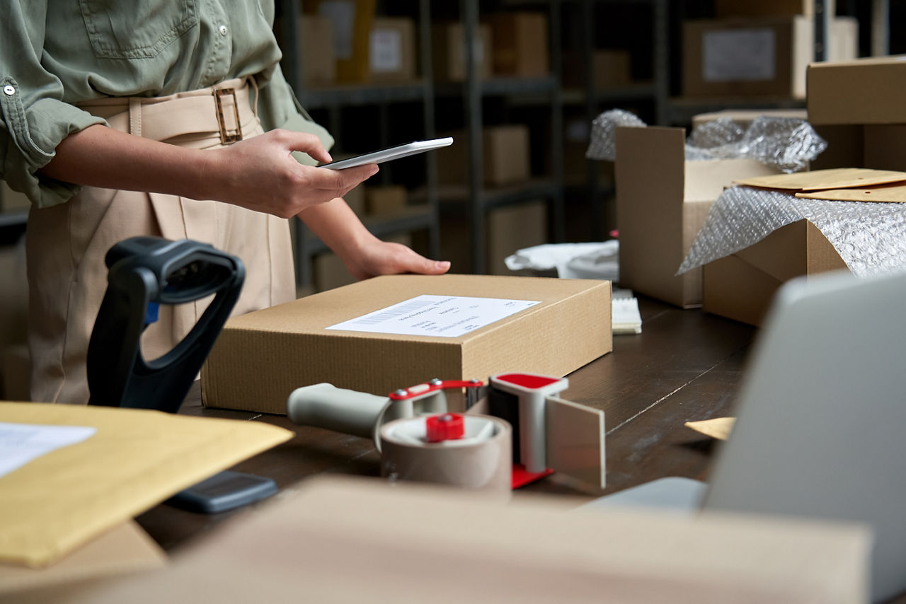 Female salesperson using mobile app on smartphone checking parcel box