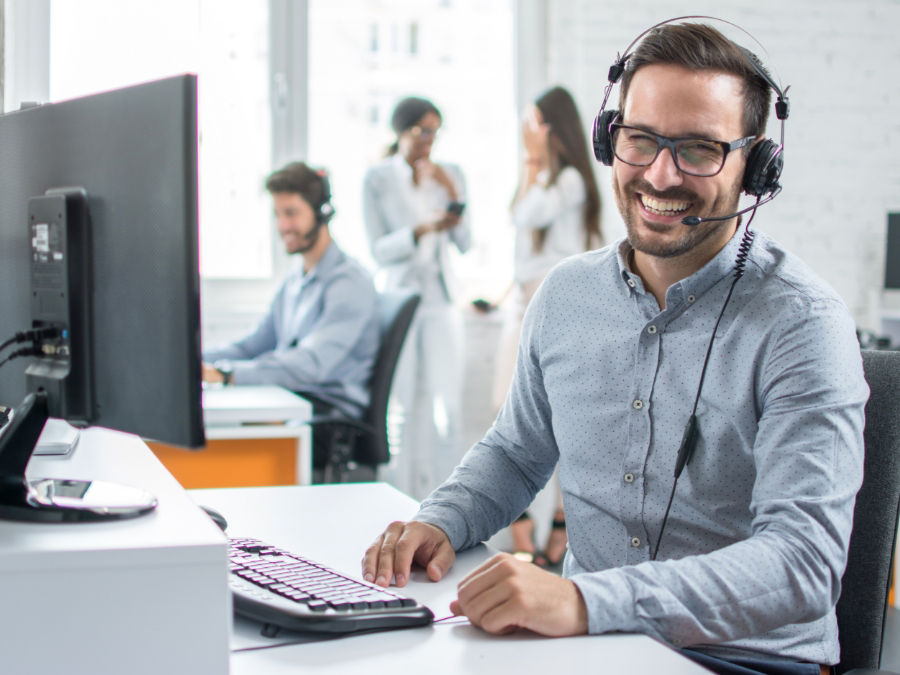 Man met headset achter computer die ondersteuning op afstand biedt