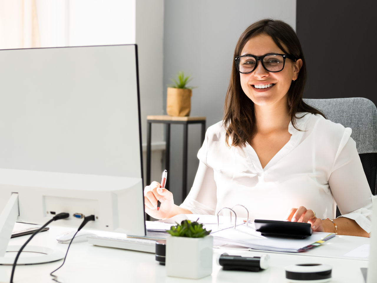 Young Professional, mit einem Notizblock und Computer in der Verwaltung arbeitet