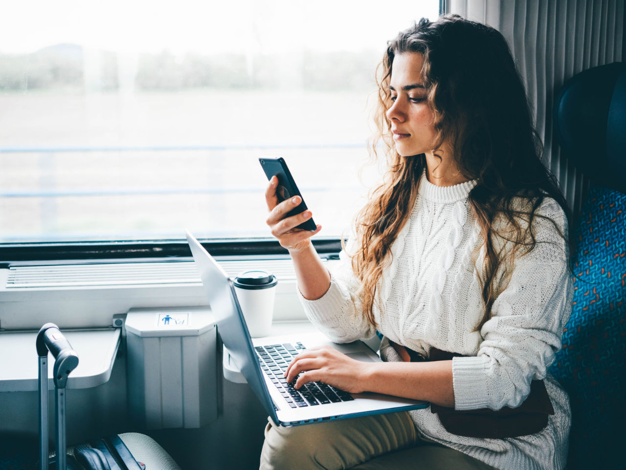 Profesional joven en un tren con una computadora portátil y un smartphone