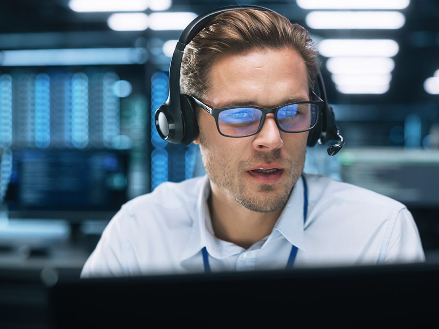 Nahaufnahme eines Technikers mit Headset am Computer