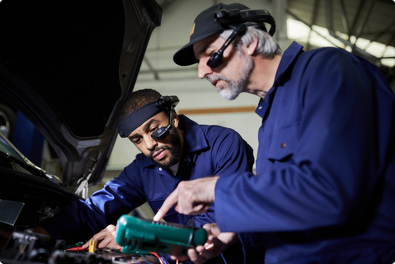 Trabalhadores da linha de frente realizando manutenção em um carro com assistência em RA