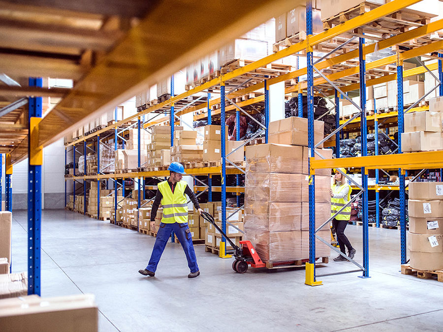 Two workers moving pellets in warehouse