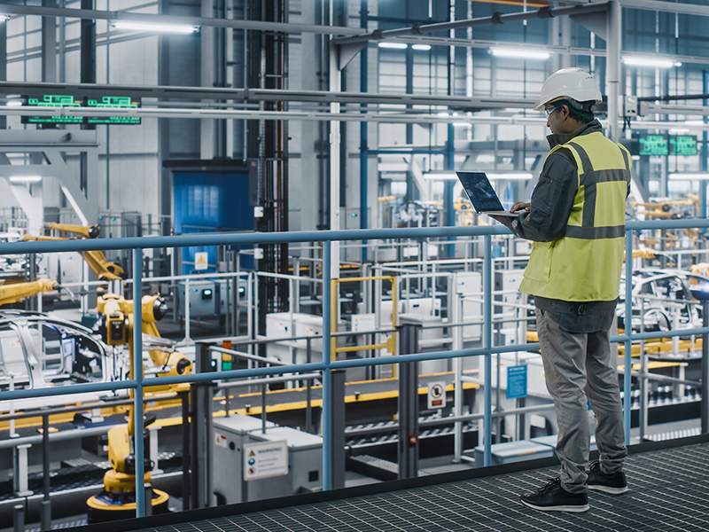 Man with laptop in automotive manufacturing plant