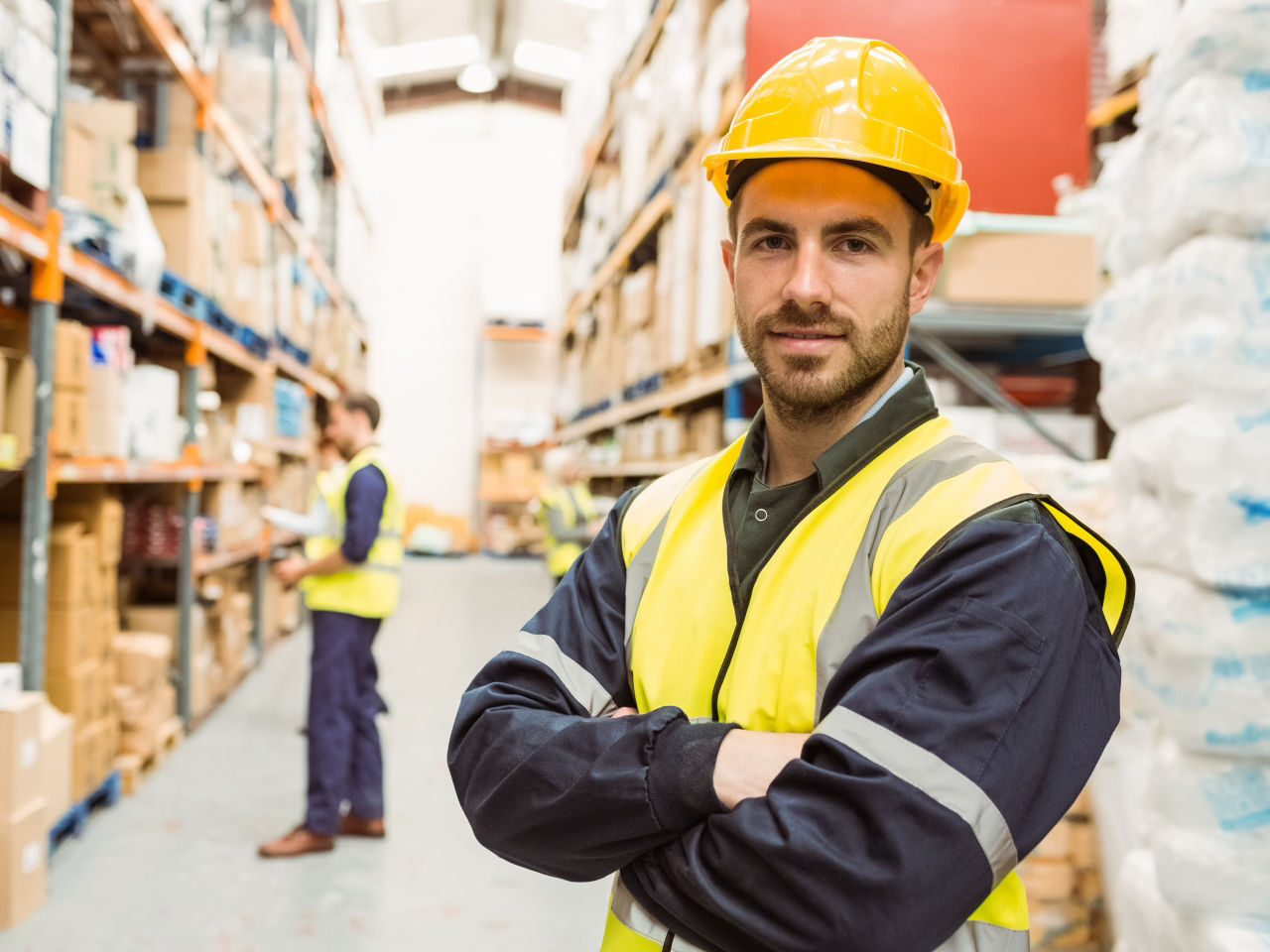 Employé d’entrepôt confiant avec les bras croisés