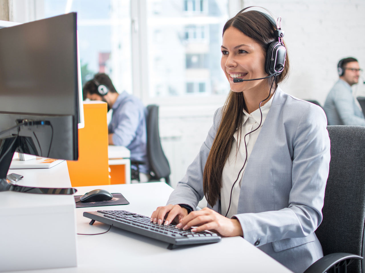 Woman with headset working on her desk giving remote support to a customer