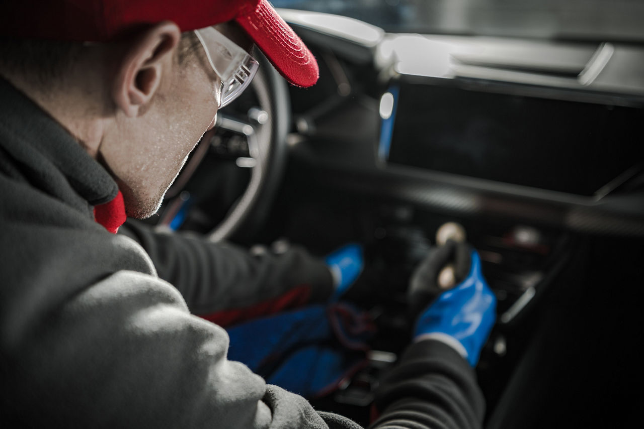 Car dealer cleaning modern vehicle dashboard