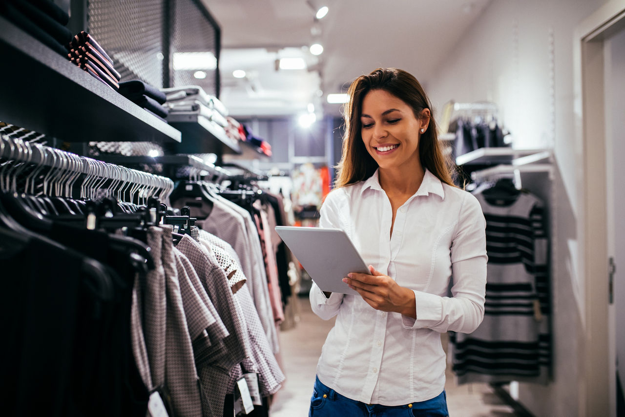 Vendeuse souriante dans un magasin, tenant un ordinateur portable et gérant l’infrastructure du commerce de détail