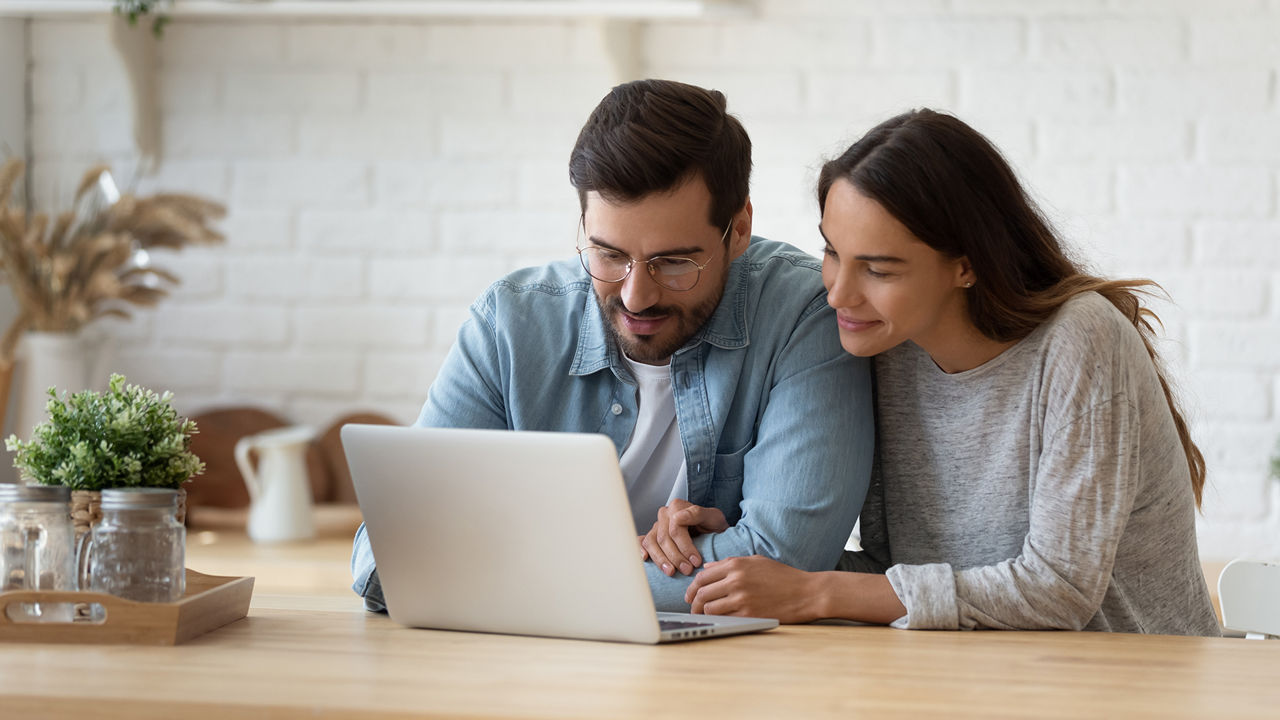 Homem e mulher sentados frente a um laptop