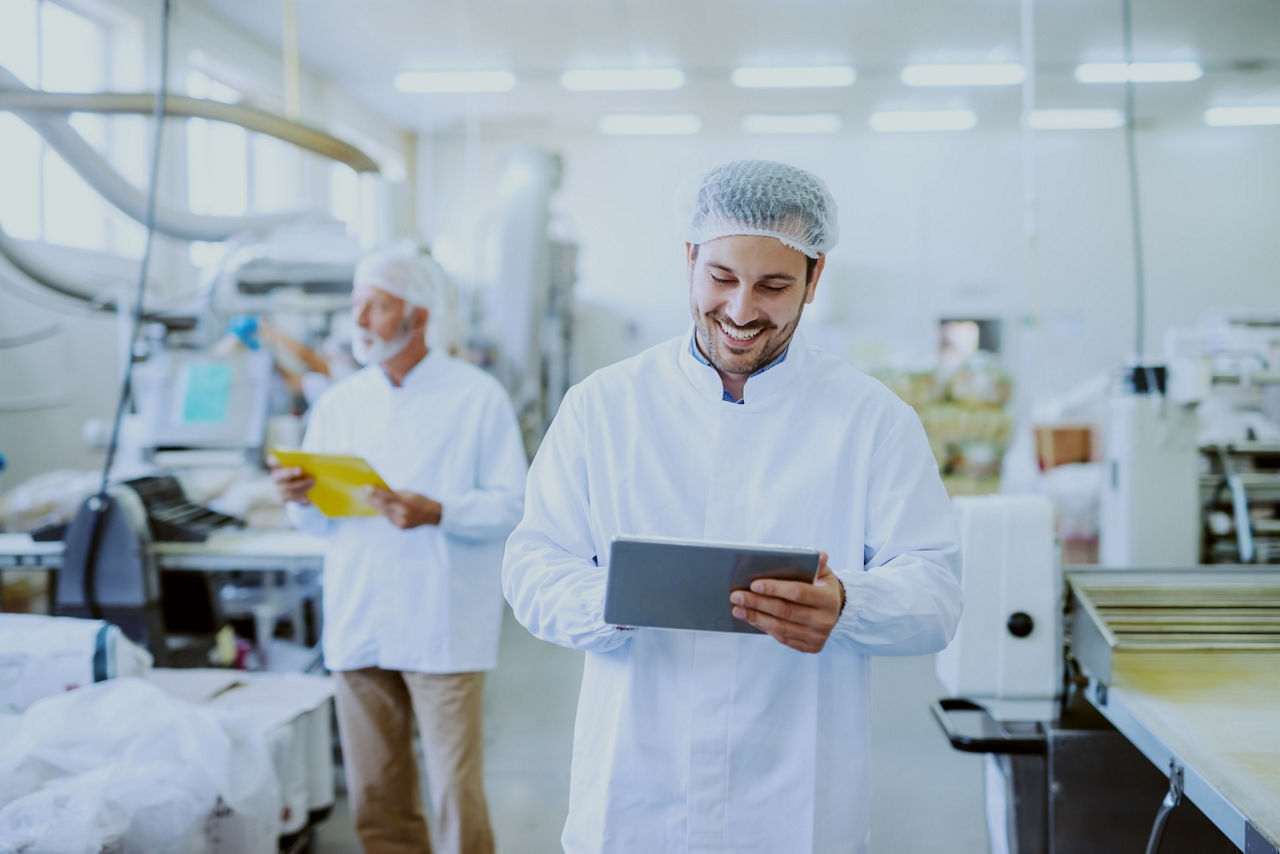 Man using tablet while standing in food plant