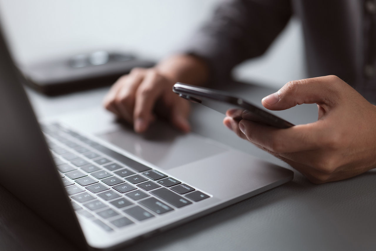 Estudante usando um laptop e um celular