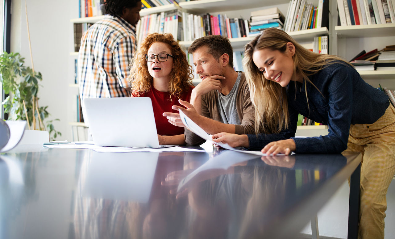 People sitting in front of a laptop brainstorming in a hybrid meeting