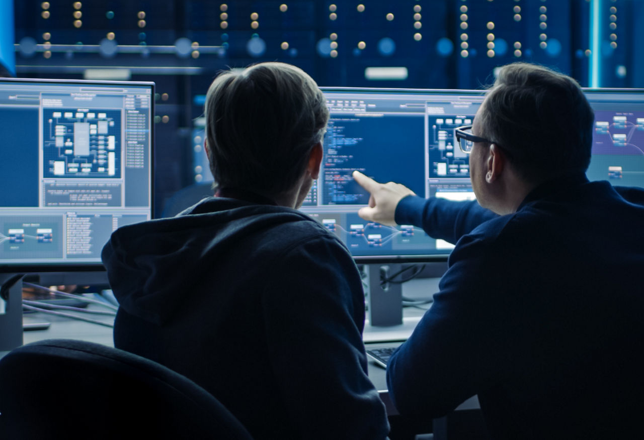 Colleagues discussing technical setup on computer