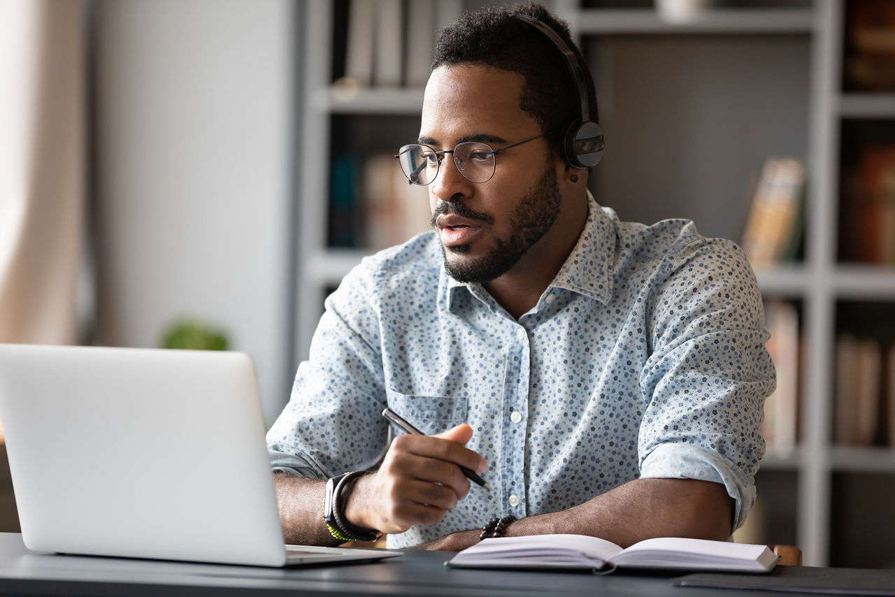 Man wearing headphones, enjoying watching educational webinar on laptop