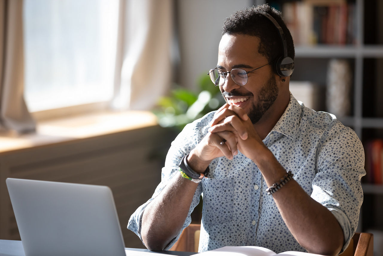 Man wearing headphones, enjoying watching educational webinar on laptop