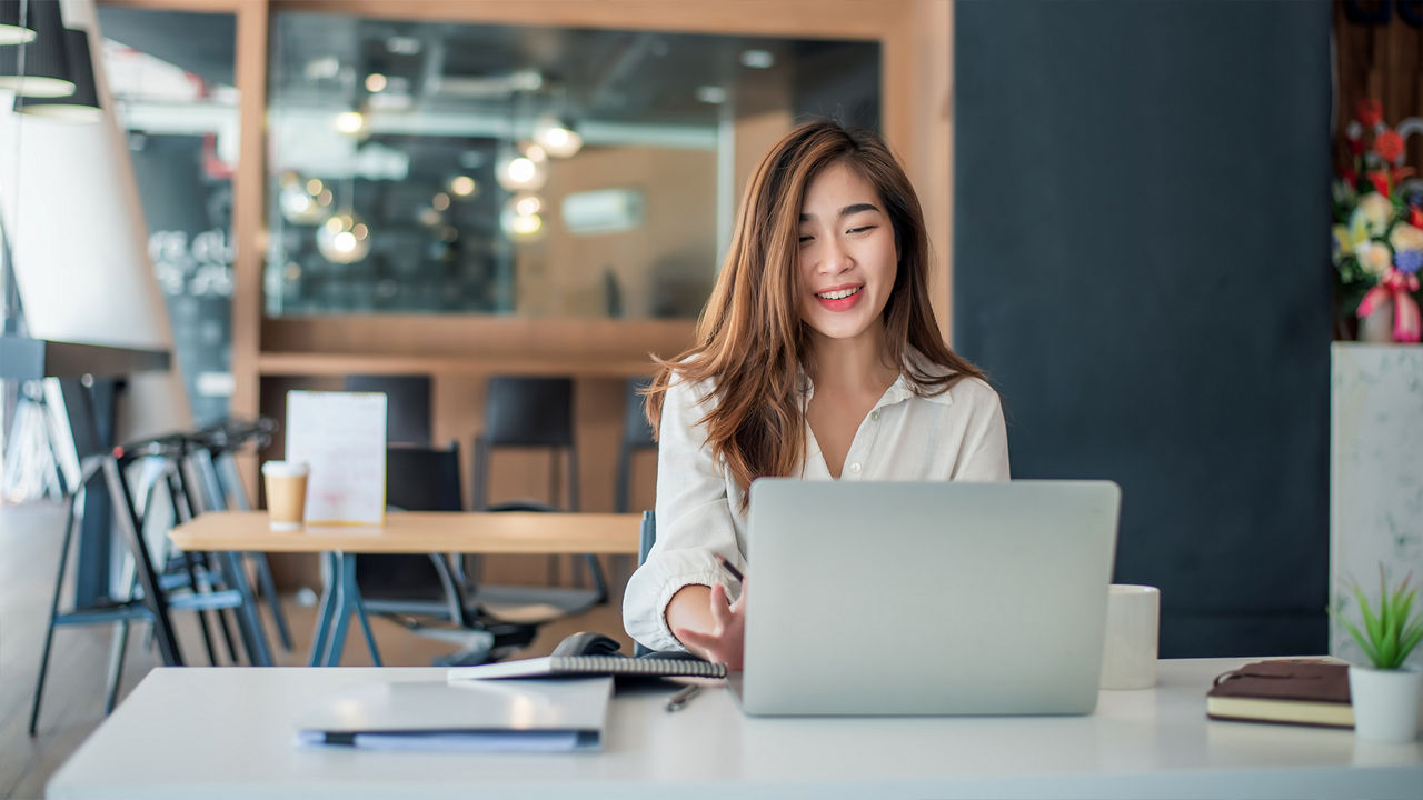 カフェテリアで自分のノート PC で作業する女性