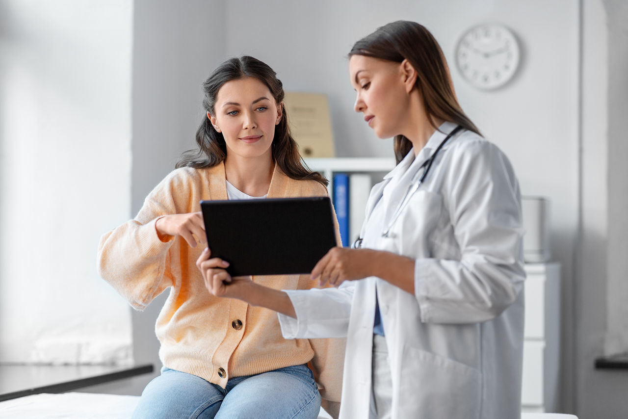 Doctor with tablet talking to patient at hospital