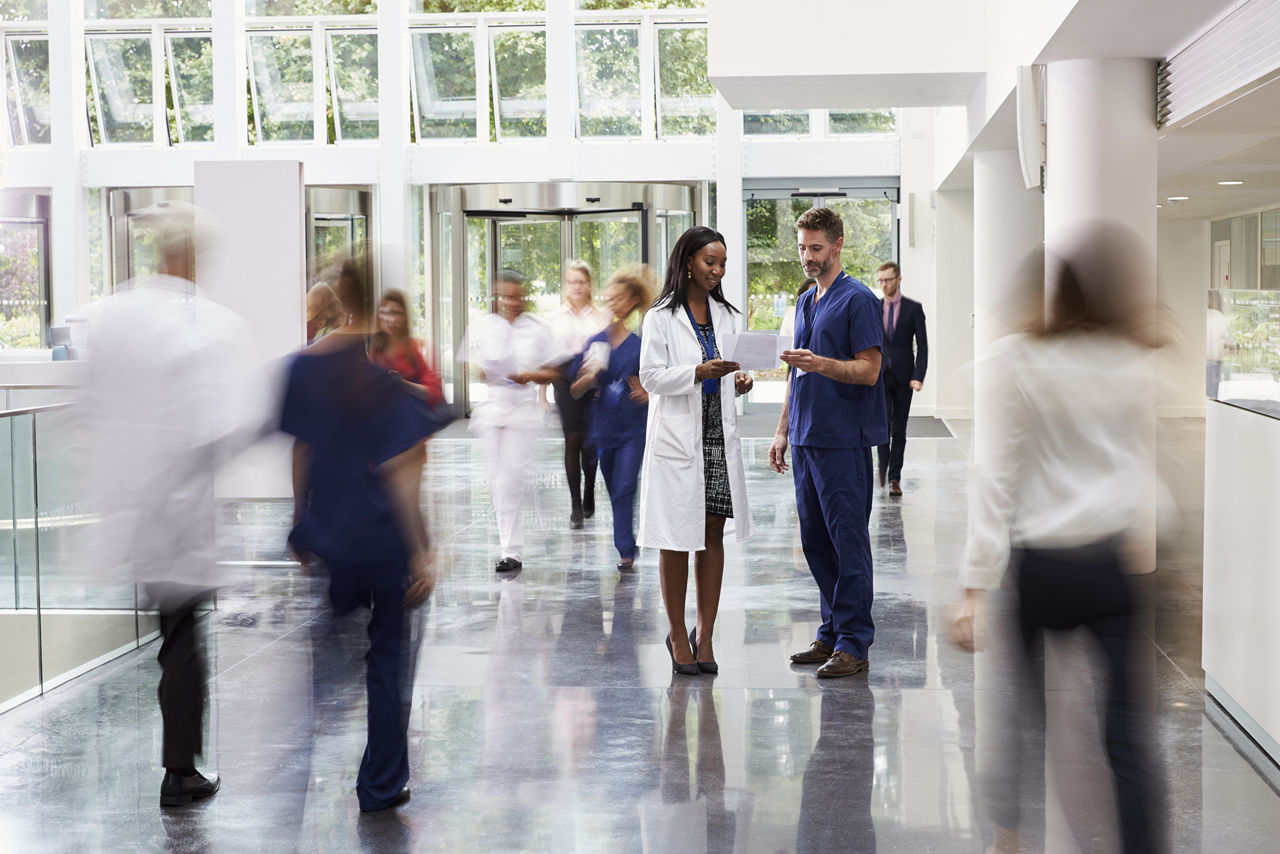 Medizinfachkräfte unter sich in einem geschäftigen Eingangsbereich einer modernen Klinik