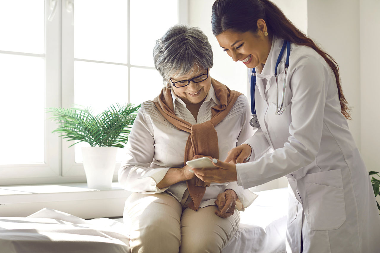 Caring doctor teaches female patient to use mobile healthcare app