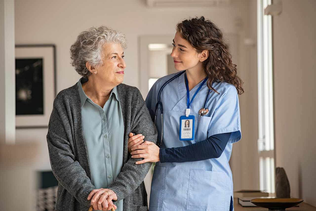 Young caregiver helping senior woman walking