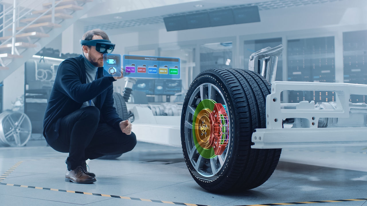 Fahrzeugingenieur bei der Montage des Fahrwerks eines Elektroautos unterstützt durch Augmented-Reality-Headset mit 3D-Software